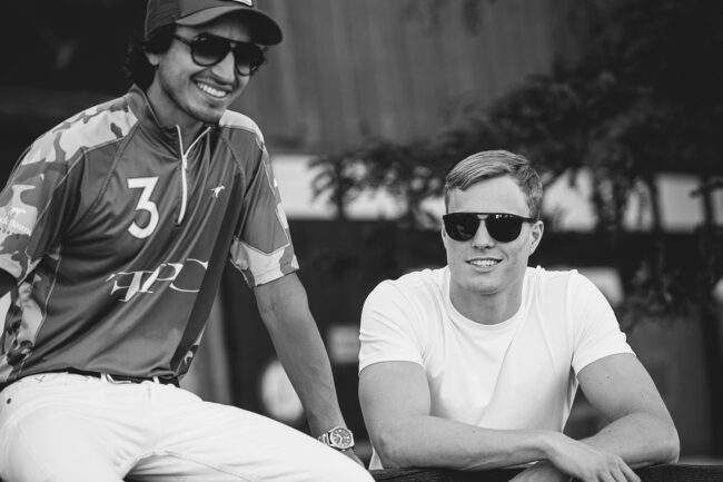 Zwei junge Männer mit Sonnenbrille lachen entspannt nebeneinander – sportliches Porträt in Schwarz-Weiß