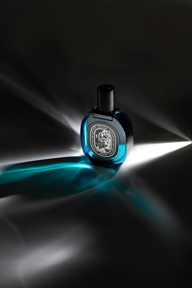 Blaues Parfumflakon von Diptyque mit dramatischen Lichtreflexen auf schwarzem Hintergrund – künstlerische Produktfotografie