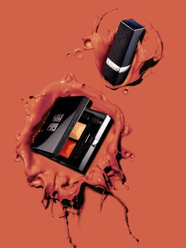 Givenchy Lidschattenpalette und Dior Lippenstift auf terrakottafarbenem Hintergrund mit Farbspritzern
